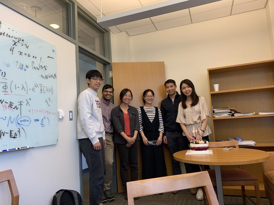 Lab members beside a whiteboard of derivations