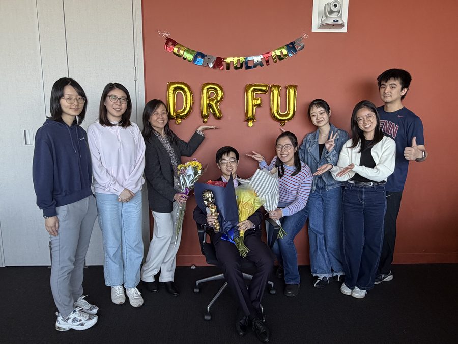 Lab members celebrating a PhD defence beneath